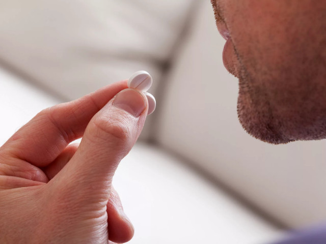 Мужчина пьет таблетку 