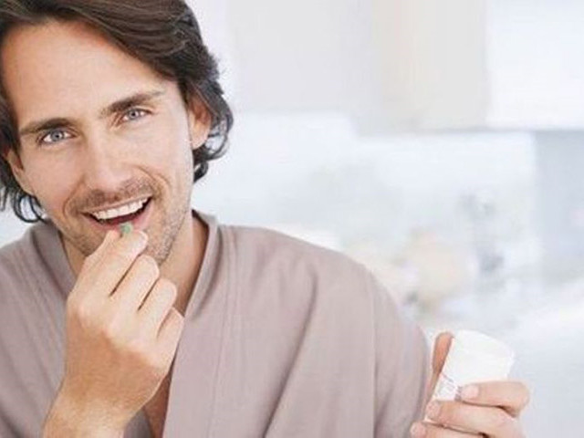 Мужчина пьет таблетку 