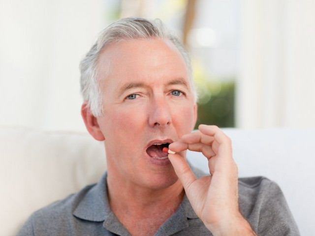 Мужчина пьет таблетку 