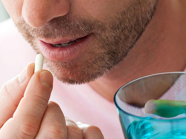 Мужчина пьет таблетку 