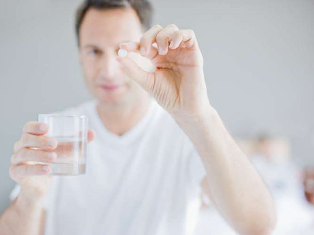 Мужчина пьет таблетку 