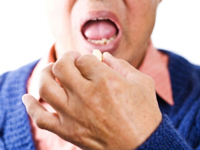 Мужчина пьет таблетку 