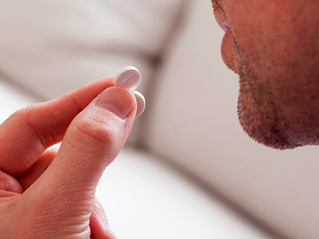 Мужчина пьет таблетку 